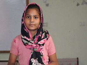 Young girl from Pakistan wearing pink shirt and a floral head scarf