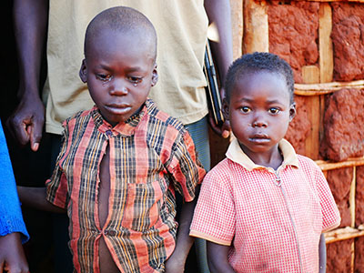 Two young children, one crying and one looking into the camera