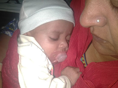 A baby girl sleeps on the chest of her caregiver
