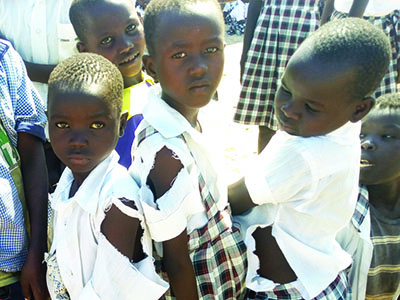 A group of three children wearing torn uniform shirts