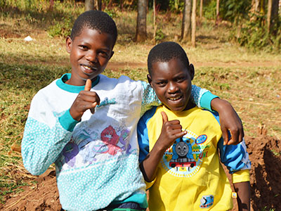 Two boys give thumbs up to the camera