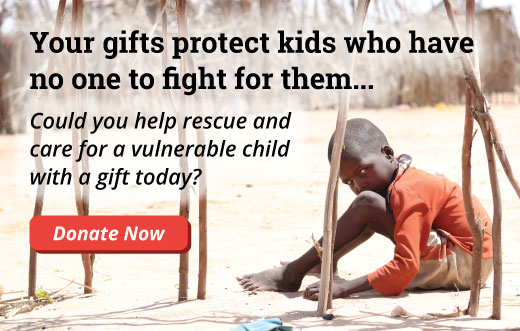 Young child in Kenya sits alone with his head resting on his knee