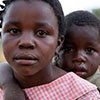 Serious young girl carries a sad young boy on her back