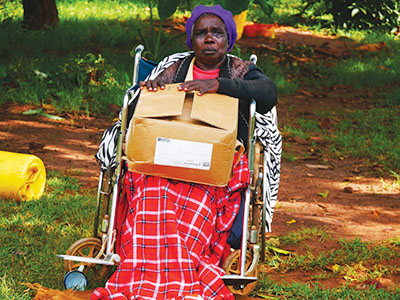 Recipient of food distribution sits in wheelchair holding box of food