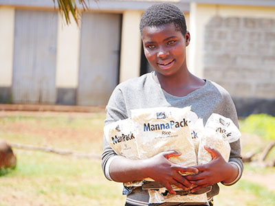 Young girl in Kenya holds packs of food in her arms