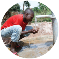 A child cupping his hands under a well in Uganda