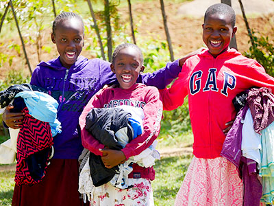Three girls in Kenya smiling with their new clothes