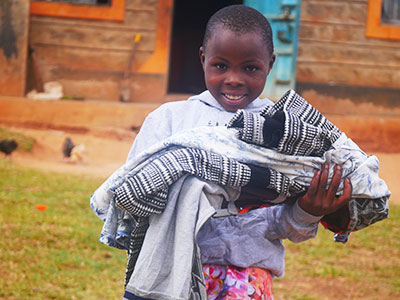 A young girl from Kenya smiles holding her new clothes