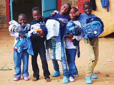 Children in Kenya smiling and holding their new clothes