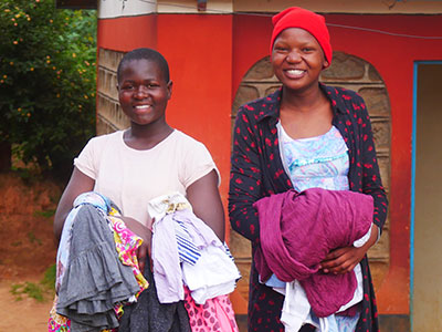 Two girls smile holding their new clothes