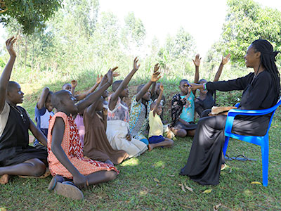 Children raise their hands hoping to be called on by their teacher