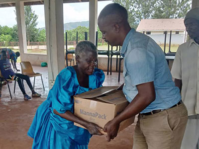 Pastor Richard giving a box of meals to an older woman