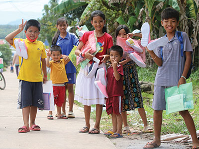 Smiling children in Cambodia holding their new school supplies