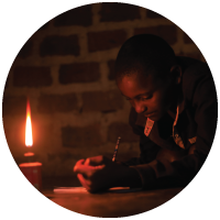 A child doing homework using a kerosene lamp for light