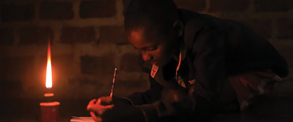 A child doing homework by candlelight