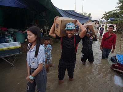 Young men carrying boxes of food through the flood waters