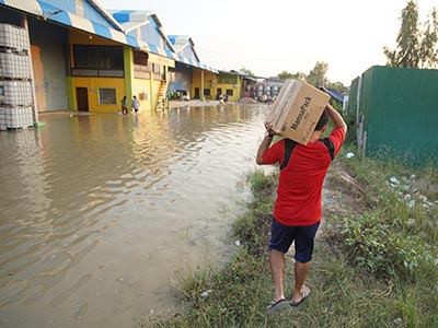 Pastor Jack walking along the flood waters carrying a box of food.