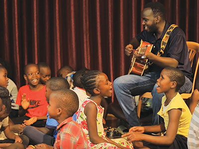 Elijah plays his guitar while singing with the children at the Kireka Kinship Project
