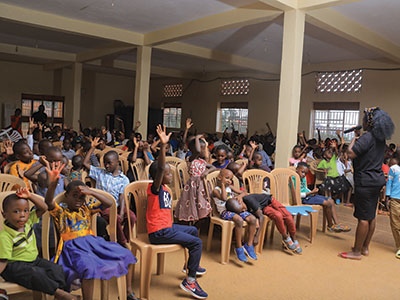 Children at the Kireka celebration raise their hands to answer a question.
