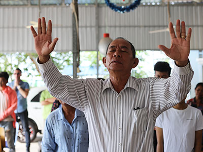 A pastor in Cambodia raises his hands in prayer