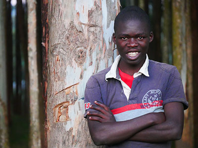 A smiling young man standing in front of a tree