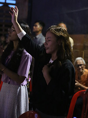 A woman raises her hand in prayer