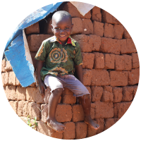 A smiling child sitting on a pile of bricks
