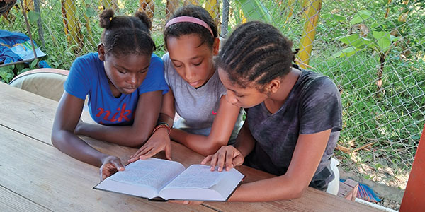 Three children reading one Bible