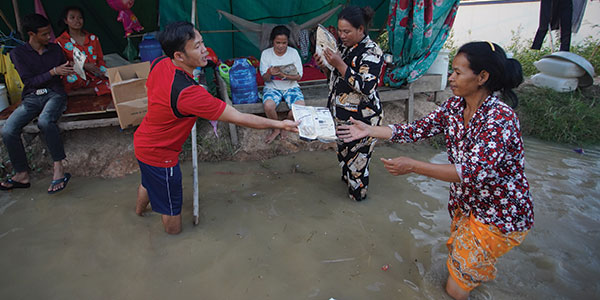 A man distributing emergency meals in flood waters
