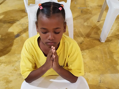 A child folding her hands in prayer