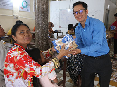 Pastor Jack handing MannaPack meals to a smiling woman.