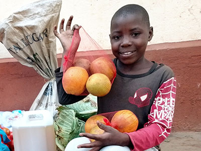 A smiling young girl holding up a bag of fruit