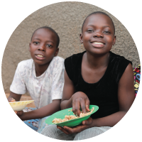 Two smiling children with their bowls of food