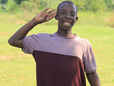 A smiling young boy saluting