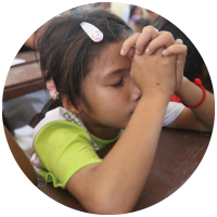 A young girl folding her hands in prayer