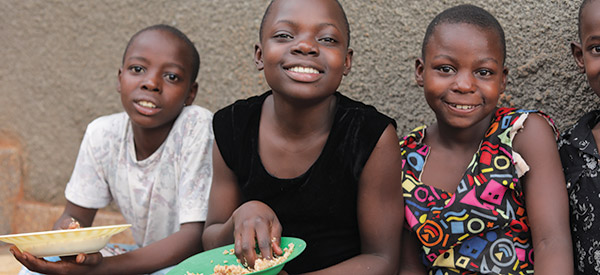 Three children smiling while eating