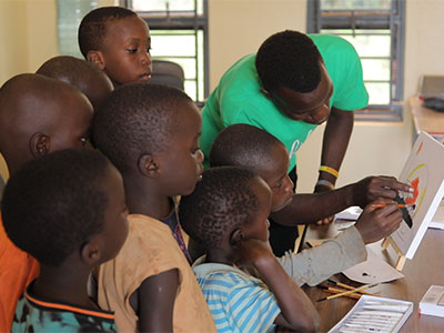 Mathias helps a younger child with their painting.