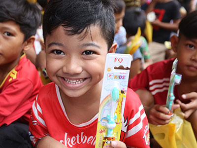 A child smiles with his new toothbrush from the Back to School Sunday School event.