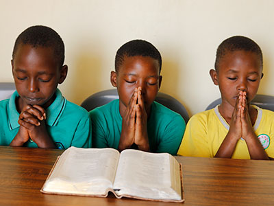 Children praying with an open Bible