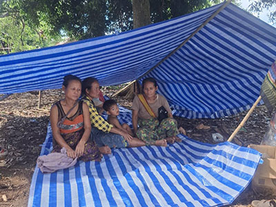 People sitting underneath their blue tarp