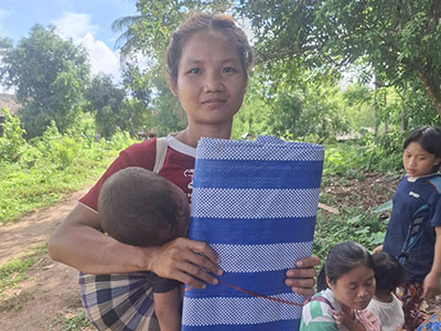 A woman holding her baby and a folded blue tarp