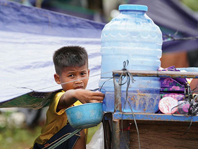 A refugee child collects water