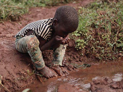 A child drinking dirty water in Uganda