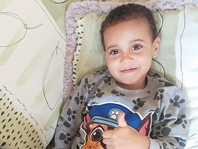 A smiling young boy giving a thumbs up
