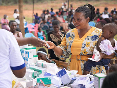 A smiling woman receives care during a medical outreach event in Uganda