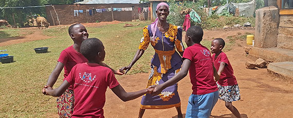 A smiling caregiver playing a game with her children