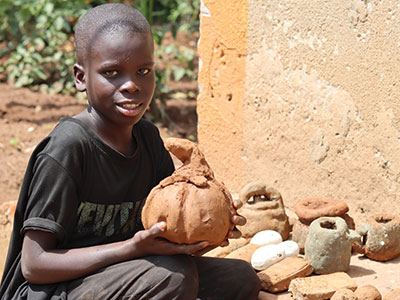 A smiling young boy holding his clay creations